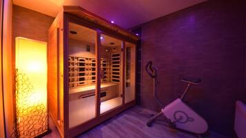 Habitación con sauna, bicicleta estática y un armario de madera con estantes.