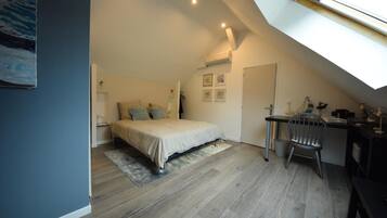 A bedroom with a bed, a desk, and a chair. There is a skylight above the bed.