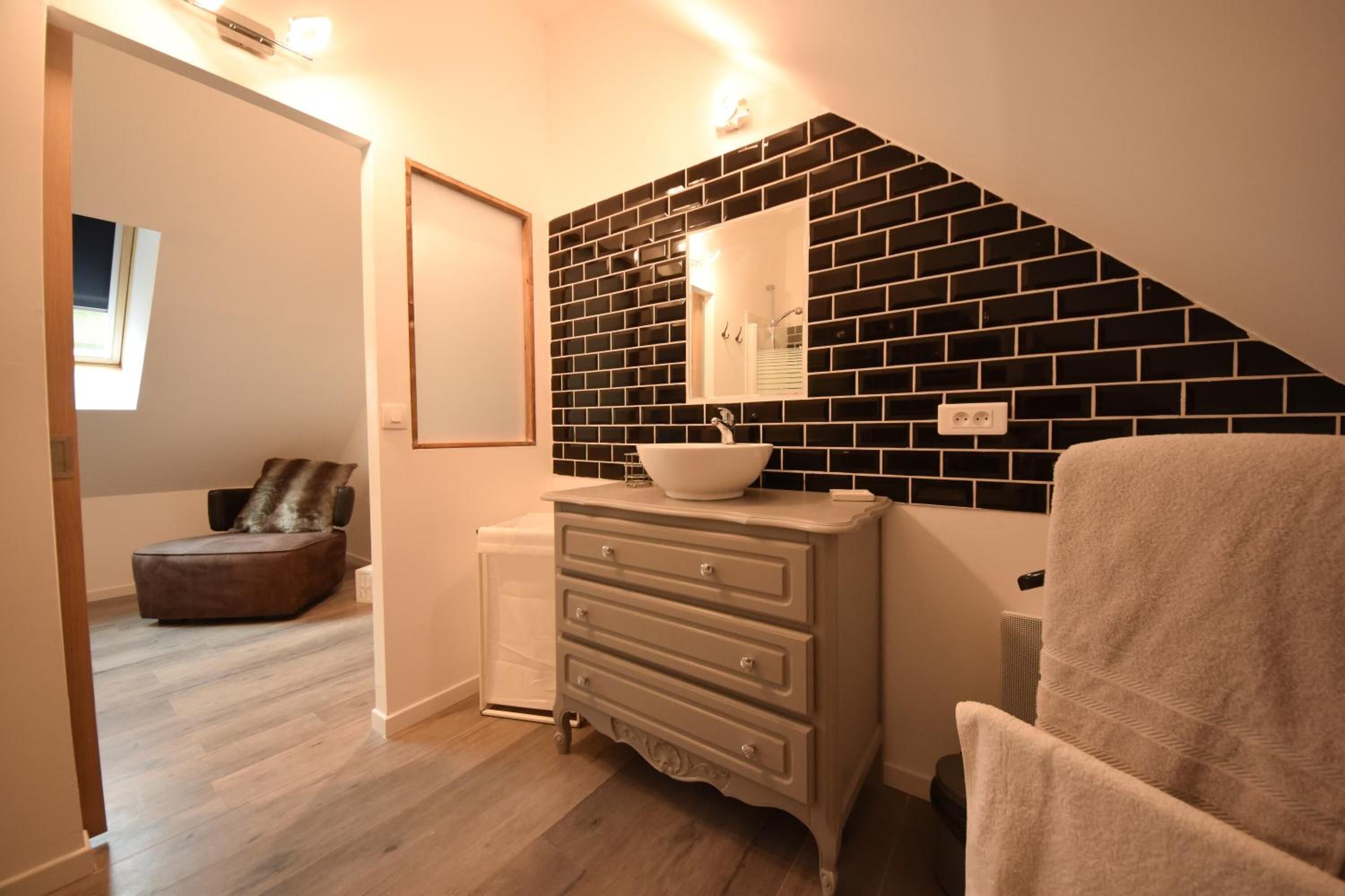 A bathroom with a black and white tiled wall, a white sink, and a beige towel.