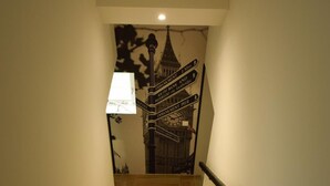 Una escalera con barandilla que lleva a una pared con un reloj y señales direccionales.