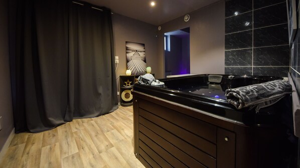 A modern bathroom with a black bathtub, wooden floor, and a star-shaped decoration on a side table.