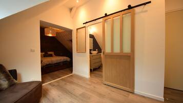A modern loft bedroom with a wooden floor, a bed, a desk, and a sliding door closet.