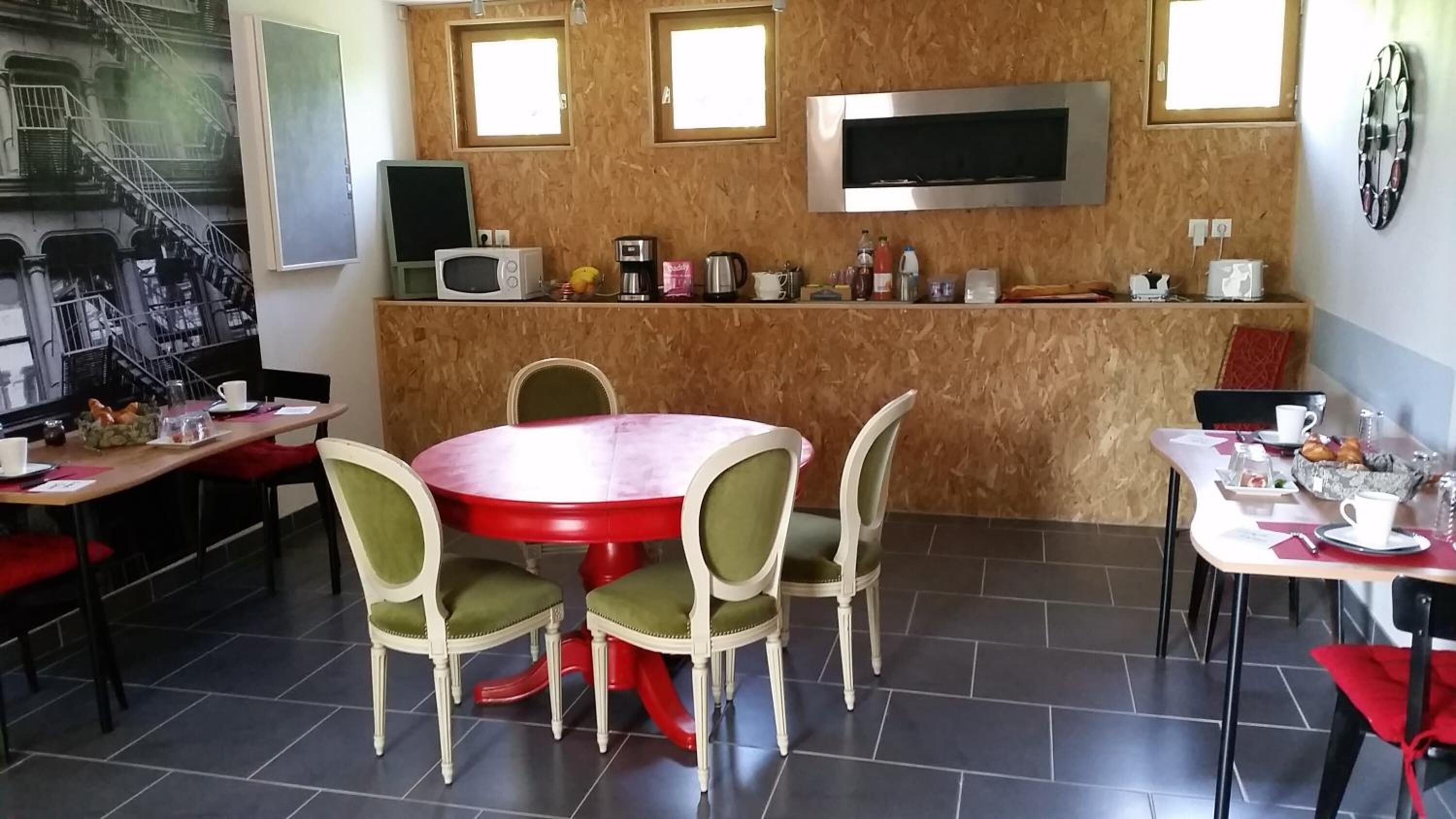 Un comedor con una mesa redonda y sillas, una encimera de cocina con electrodomésticos y un televisor colgado en la pared.