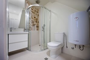 A modern bathroom with a glass-enclosed shower, a white toilet, and a Bosch water heater.
