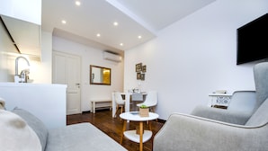 A modern living room with a sofa, a coffee table, and a TV mounted on the wall. - Luna Rooms and Studios (Rovinj)