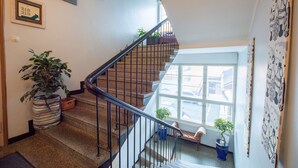 A staircase with a metal railing, potted plants, and a window with a view of the street. - Hostel Buisto (Pori)