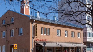 A building with a clock tower, a sign reading "Paloasema," and a storefront with awnings. - Hostel Buisto (Pori)