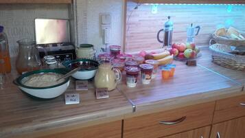 A kitchen counter with various food items and containers, including jars of preserves, a bowl of oatmeal, and a pitcher of milk.