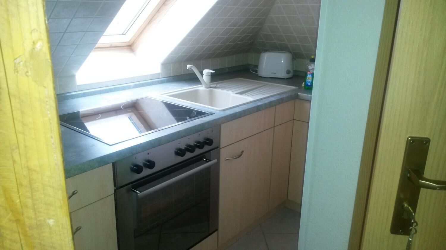 Eine kompakte Küche mit Einbauofen, Spüle und Toaster.