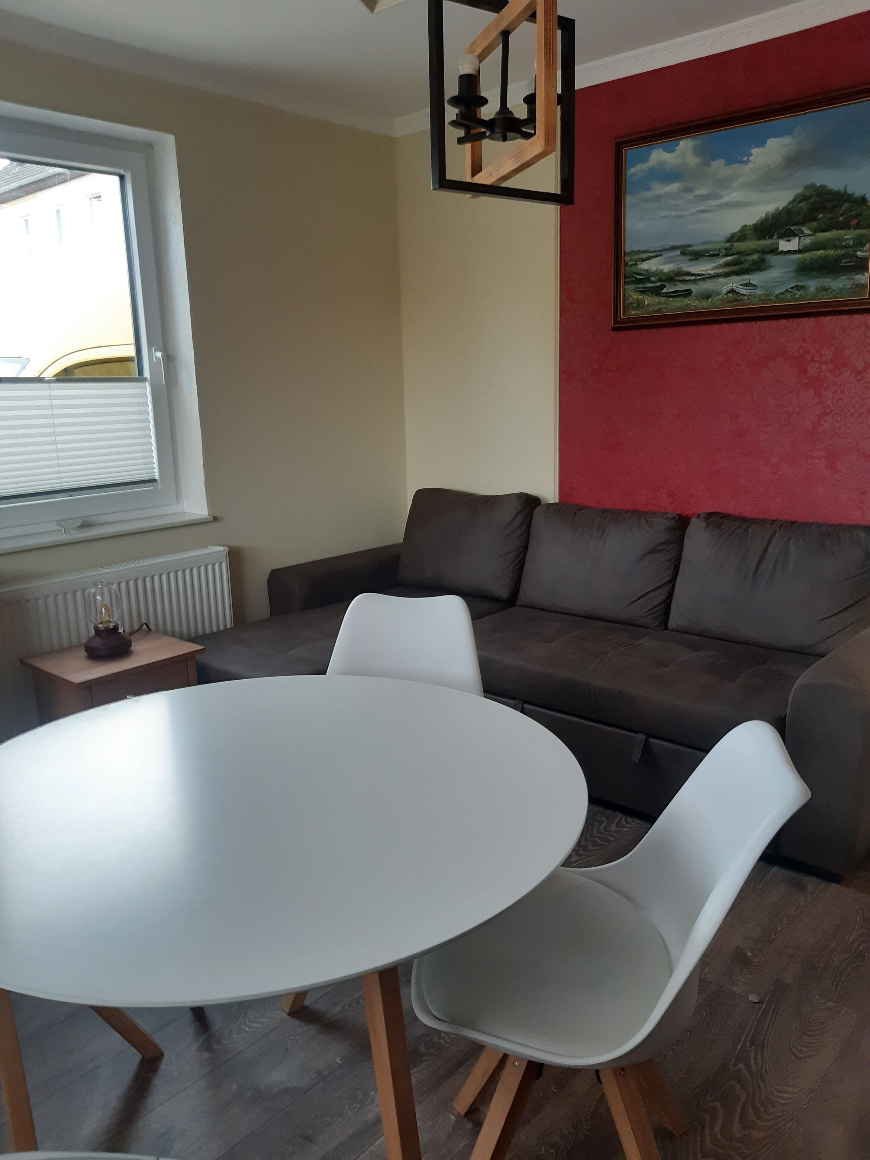 A living room with a brown sofa, a white table, and a painting on the wall.