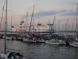Uma marina com vários barcos atracados, incluindo um navio grande ao fundo.