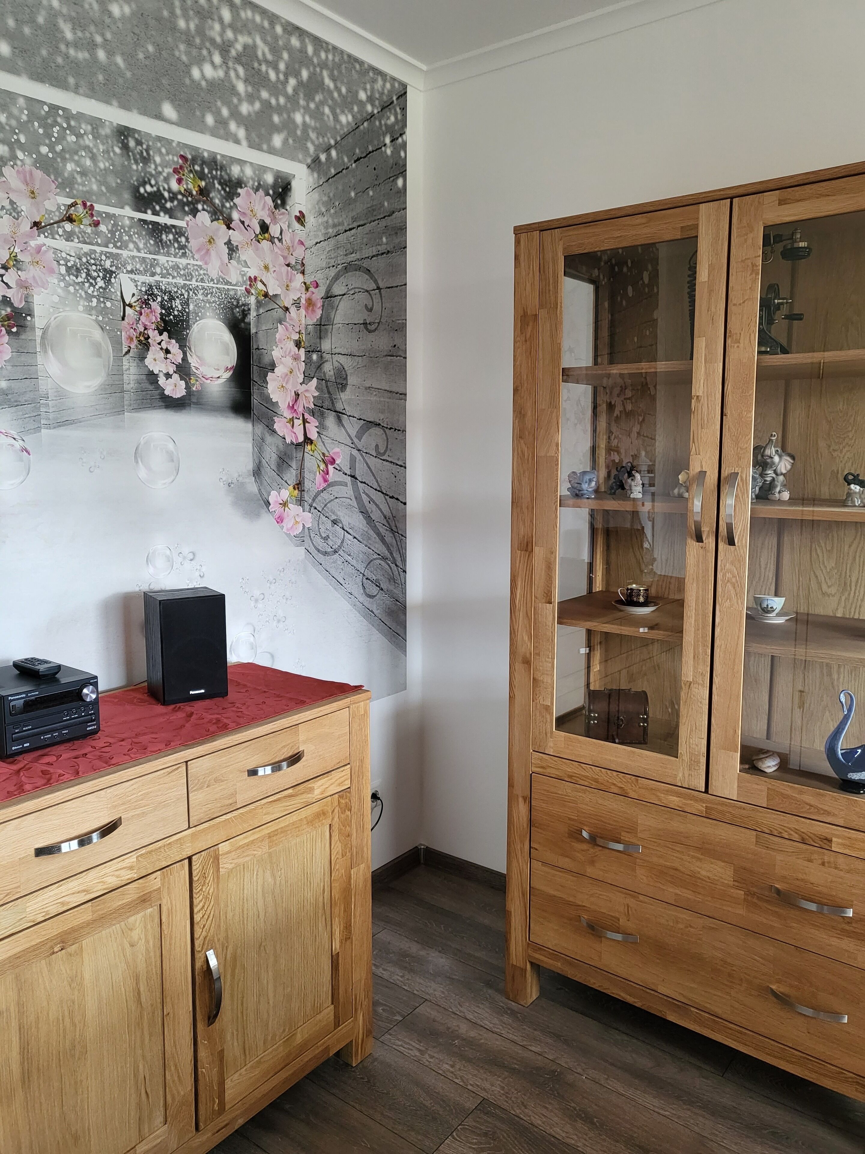 Un mueble de madera con puertas de cristal y un paño rojo sobre un tocador de madera.