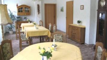 Un comedor con una gran mesa ovalada, sillas, un aparador de madera y un reloj en la pared.