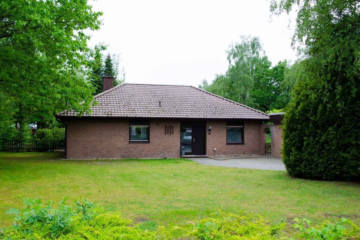 Une maison de plain-pied en briques, avec un toit en tuiles, une porte d’entrée et un petit jardin à l’avant.