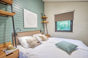 A bedroom with a bed, bedside tables, a window, and a wall-mounted artwork.