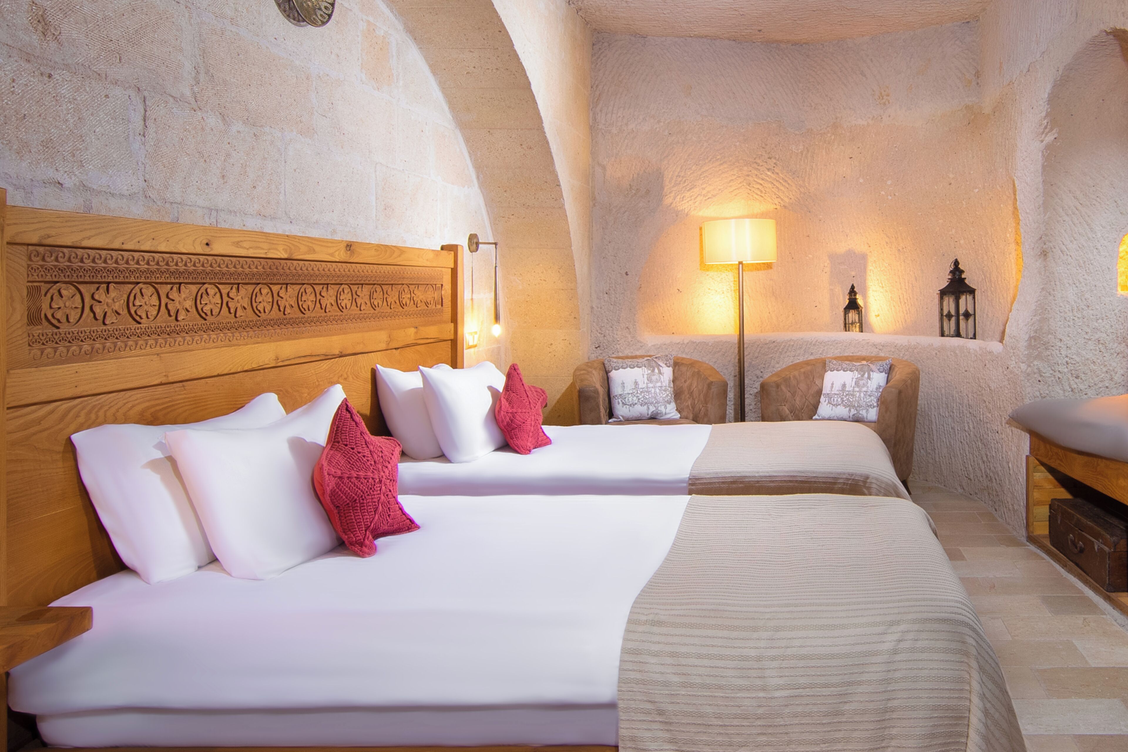 Une chambre d’hôtel avec deux lits, une tête de lit en bois et un mur en pierre.