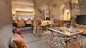 A cozy living room with a sofa, chairs, a coffee table, and a television. - The Rupestral House Hotel (Nevsehir)