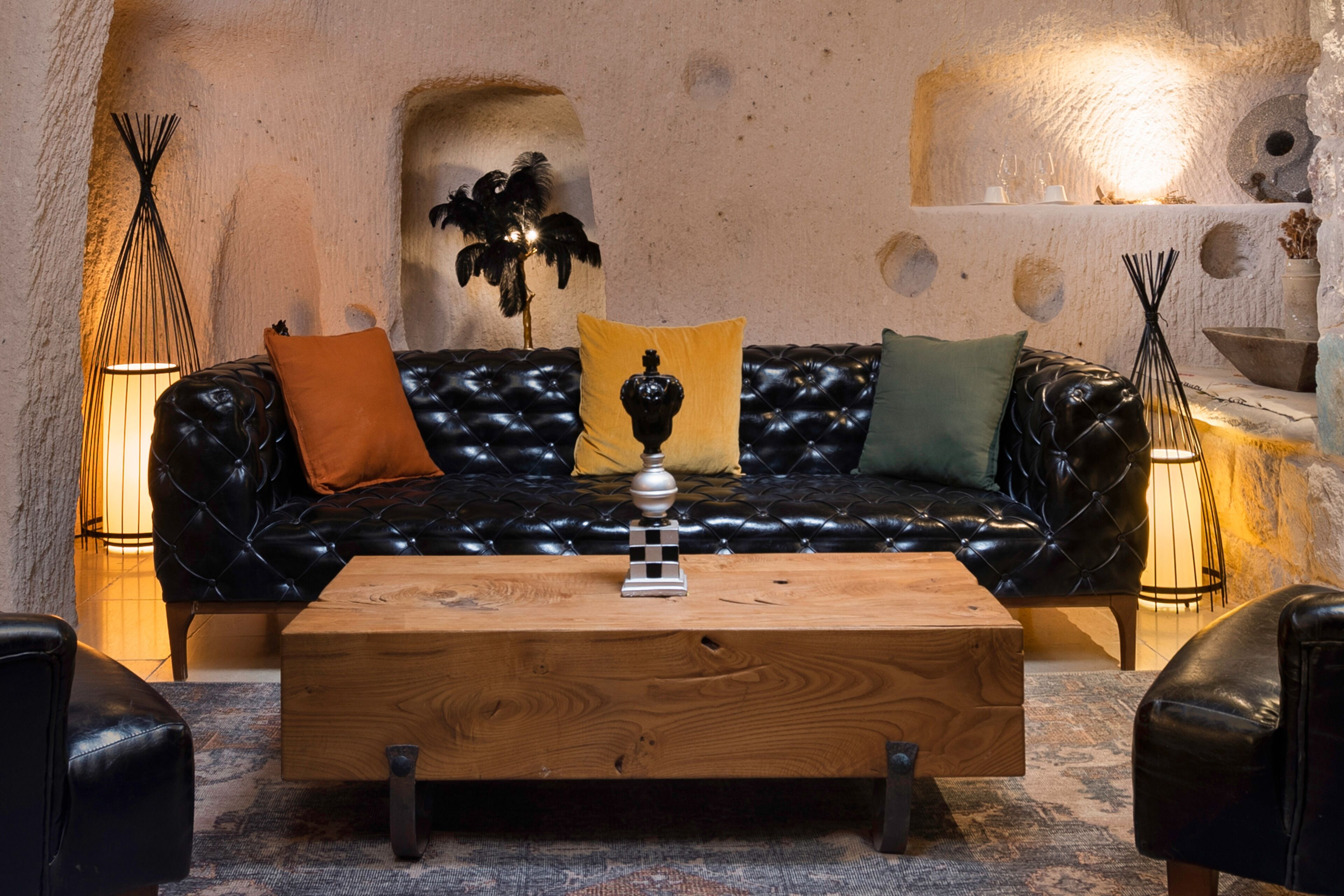 A cozy living room with a black leather sofa, wooden coffee table, and two black leather armchairs.