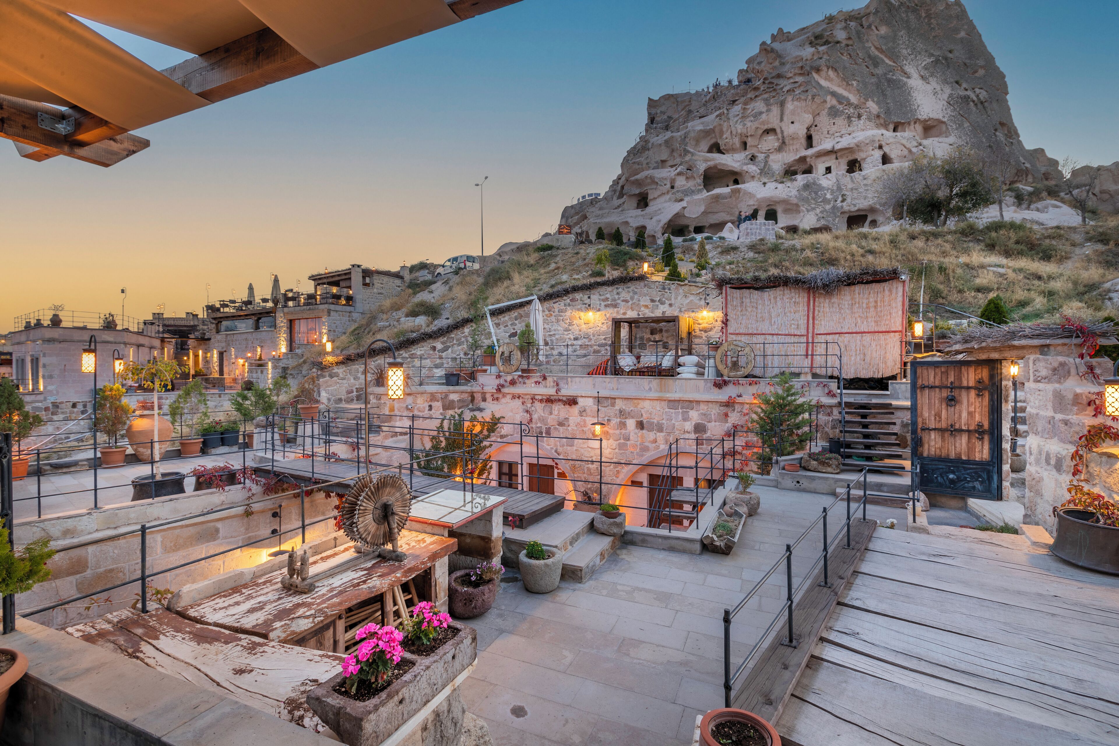 A rooftop terrace with stone walls, potted plants, and outdoor seating.
