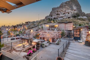Una terraza en la azotea con paredes de piedra, plantas en macetas y mobiliario de exterior.