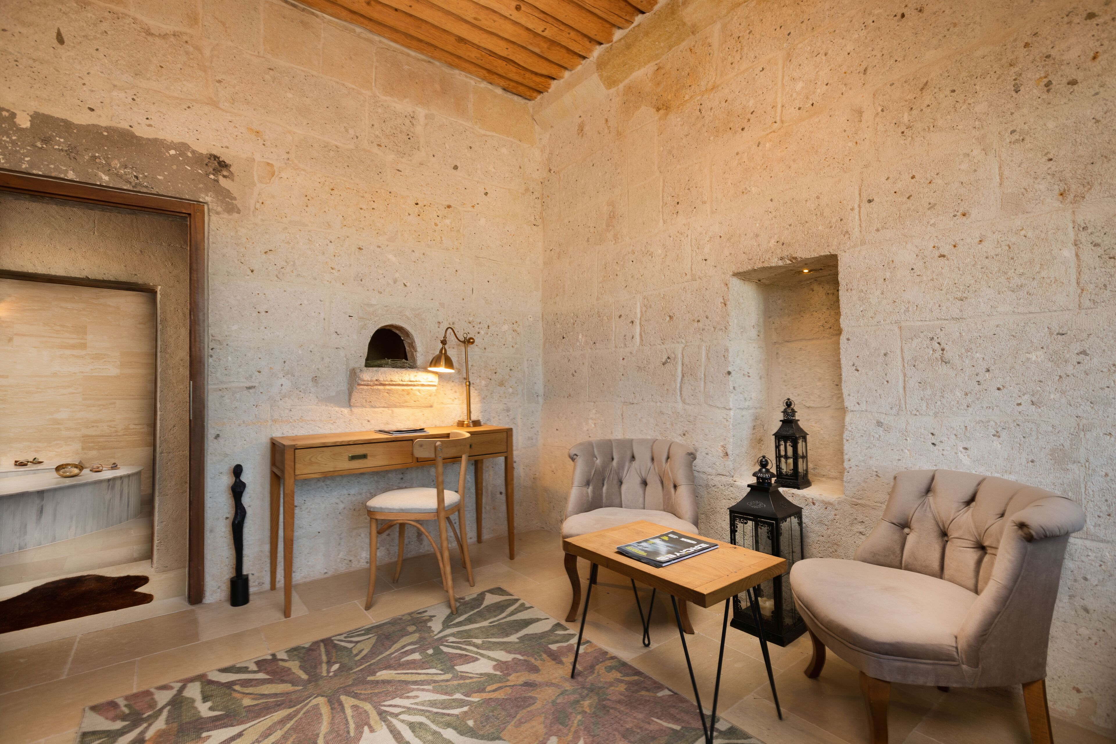 Une pièce chaleureuse avec un bureau en bois, deux chaises, une petite table et un tapis à motifs.