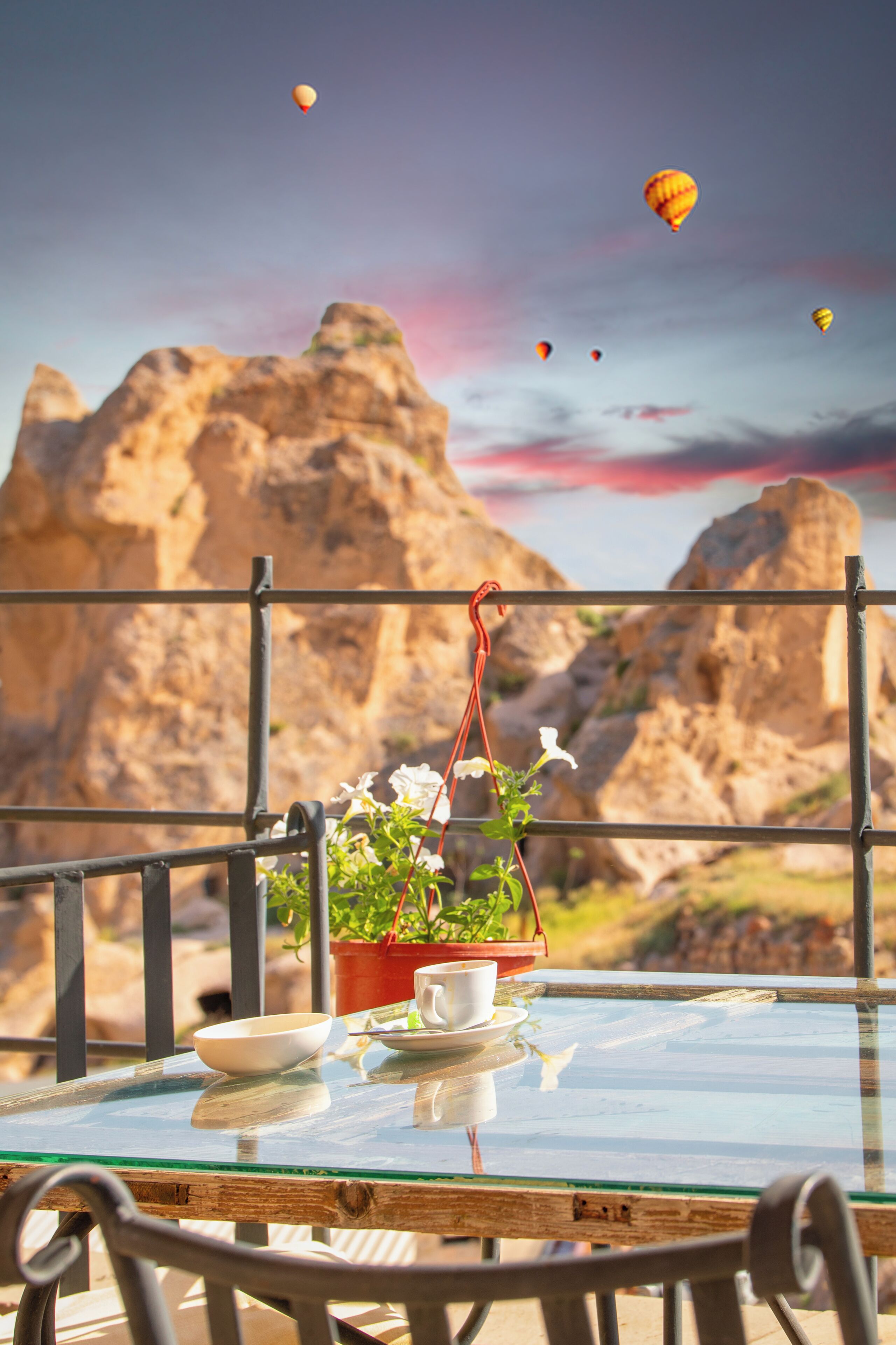 Une table en verre sur laquelle se trouvent un bol blanc, une tasse blanche et un pot rouge contenant des fleurs blanches.