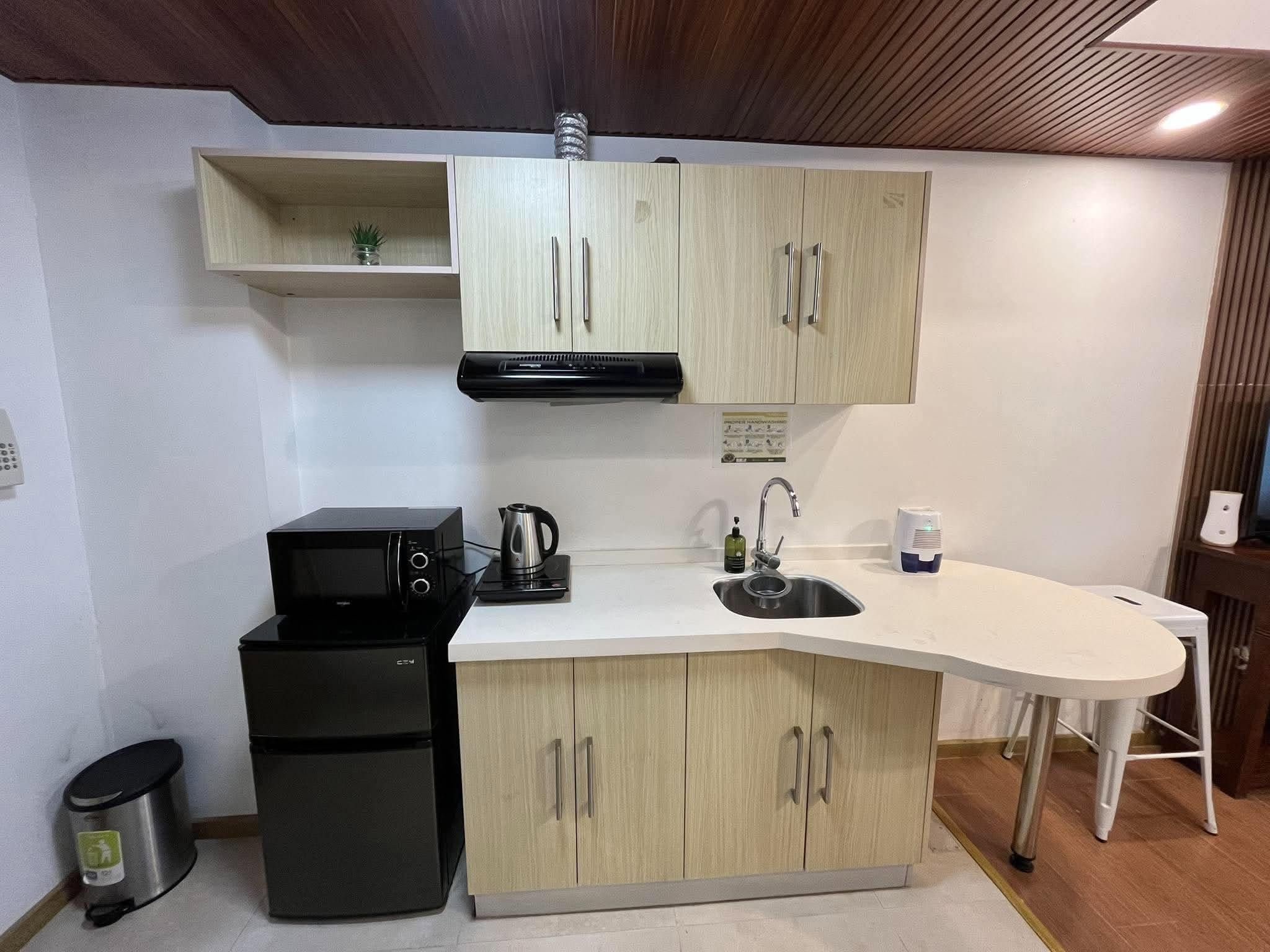 A compact kitchen with a microwave, stove, sink, and a small refrigerator.