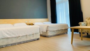 Ett hotellrum med två sängar, en sänggavel i trä, ett bord och ett stort fönster med mörka gardiner.