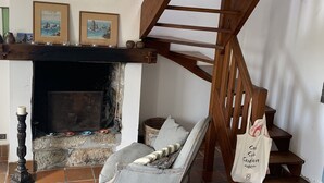 Una sala de estar acogedora con chimenea, una escalera de madera y un sillón cómodo.