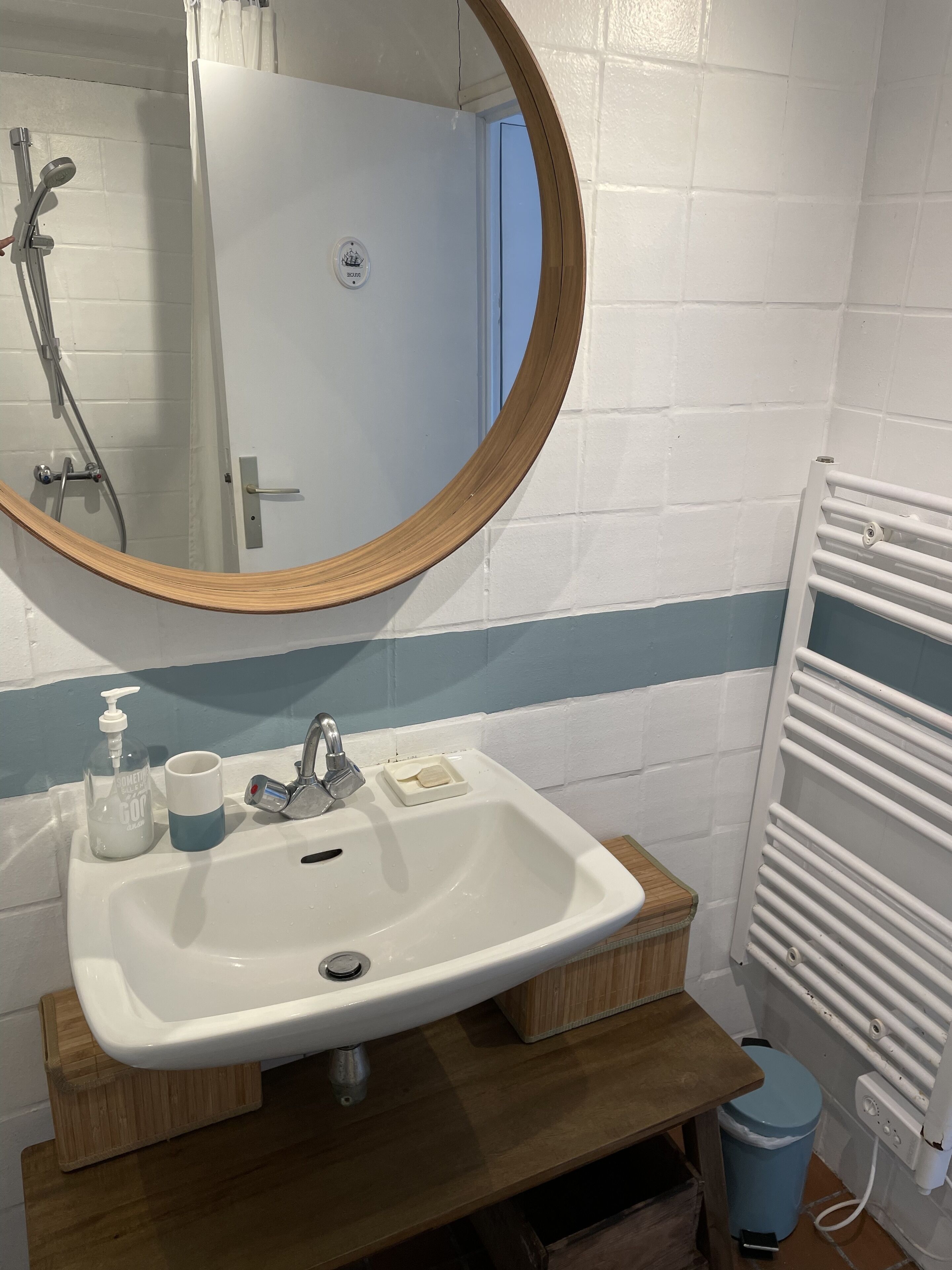 Ein Badezimmer mit Waschbecken, Spiegel, Dusche und Handtuchhalter.