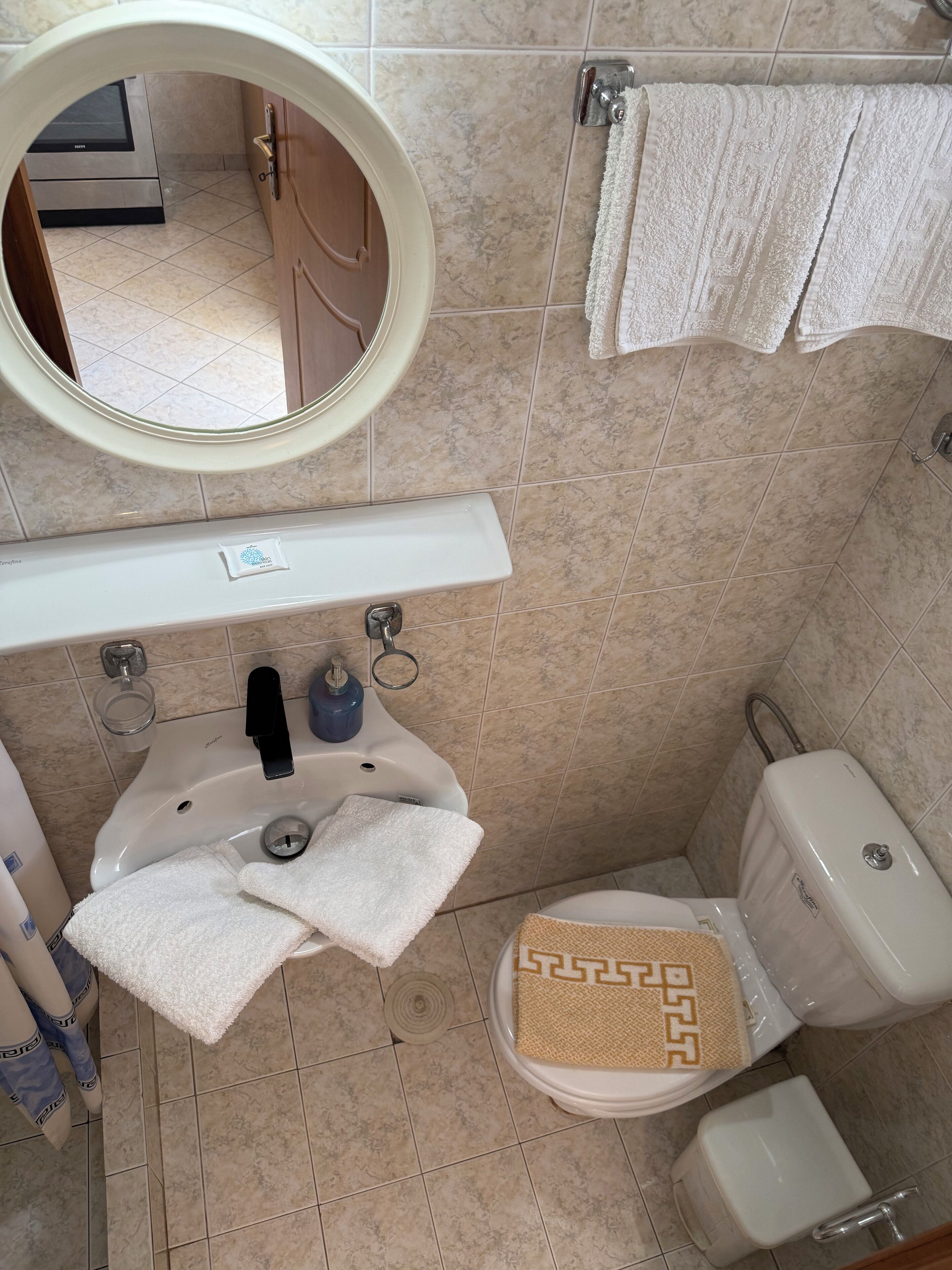 A bathroom with a sink, mirror, towel rack, toilet, and a bidet.