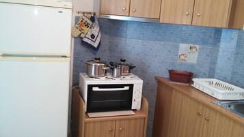 Una cocina compacta con un refrigerador blanco, un horno microondas y armarios de madera.