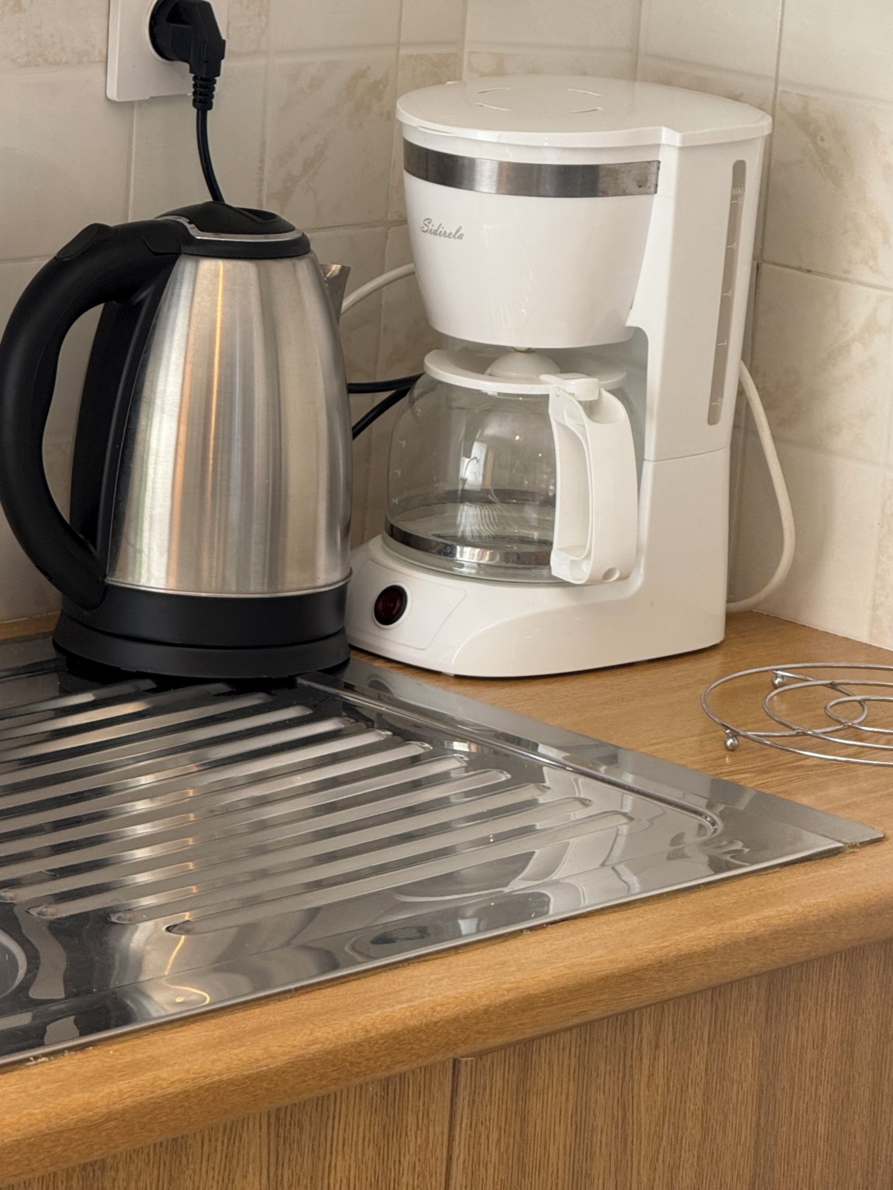A kitchen with a coffee maker and a kettle on the counter.
