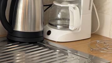 A kitchen with a coffee maker and a kettle on the counter.