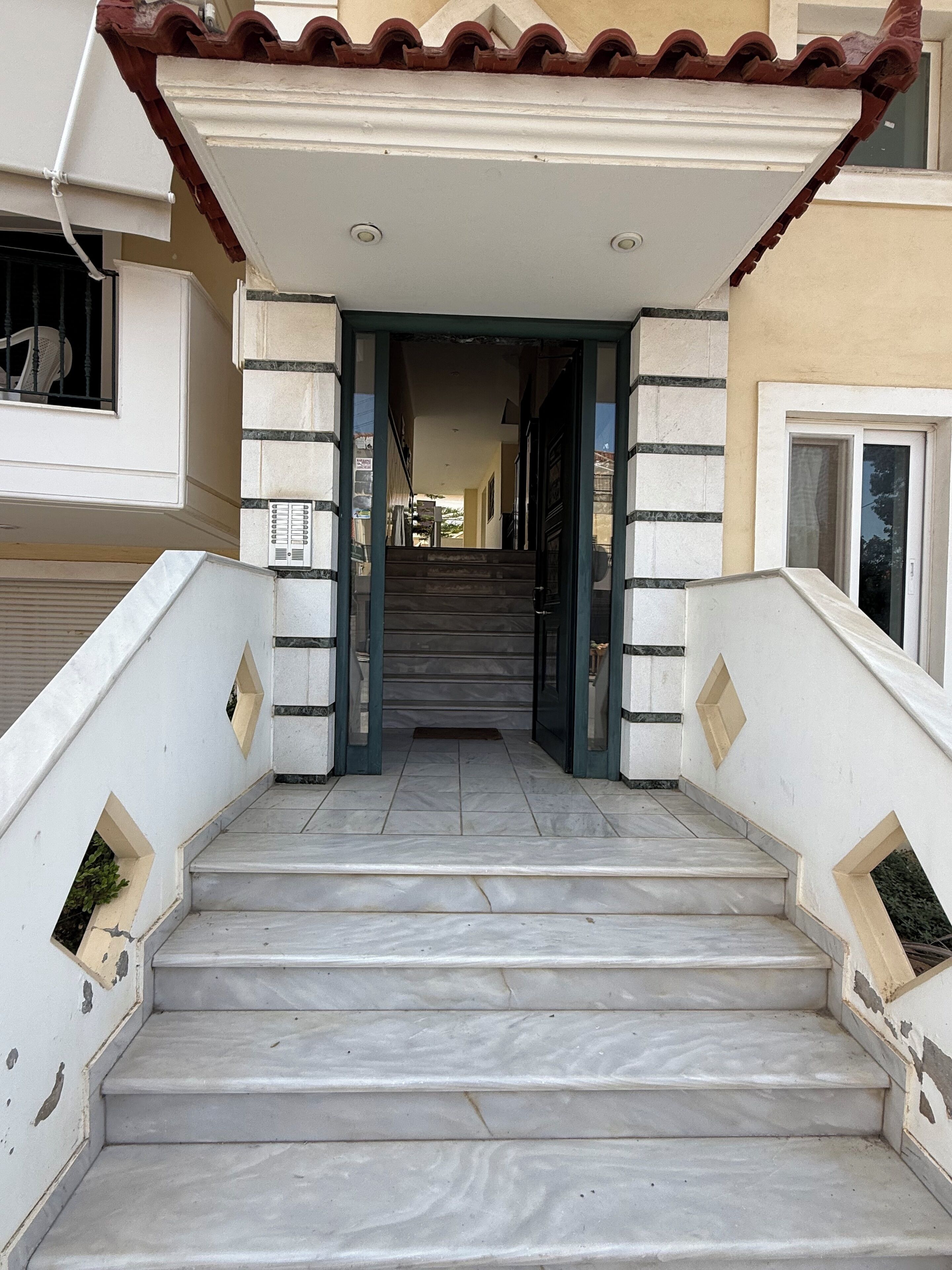 Una escalera que lleva a la entrada de un edificio con techo de tejas y fachada blanca.