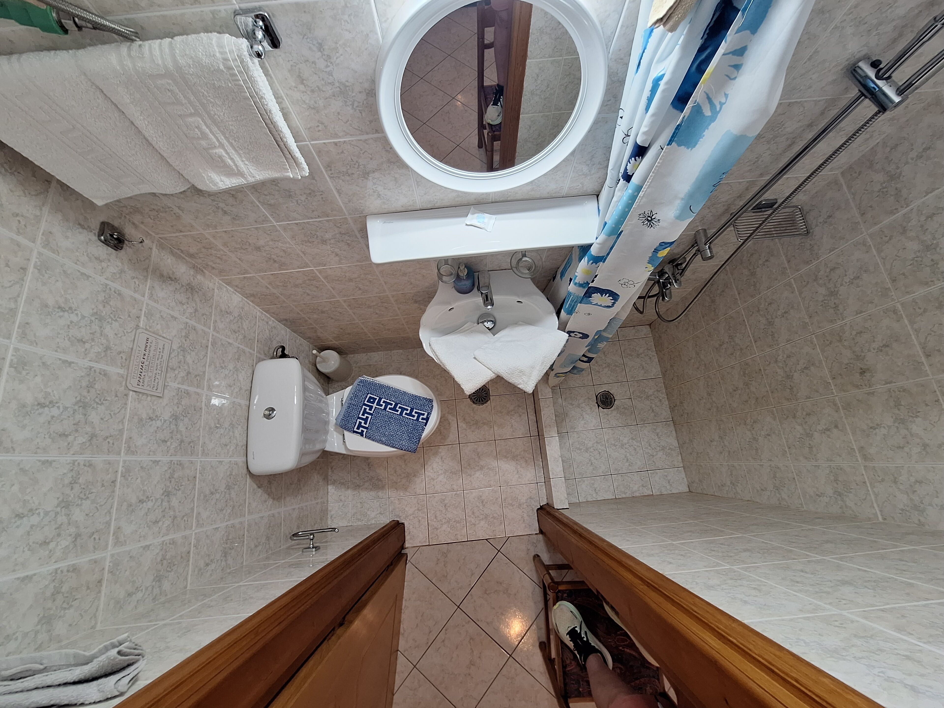 A bathroom with a toilet, sink, mirror, and shower area.
