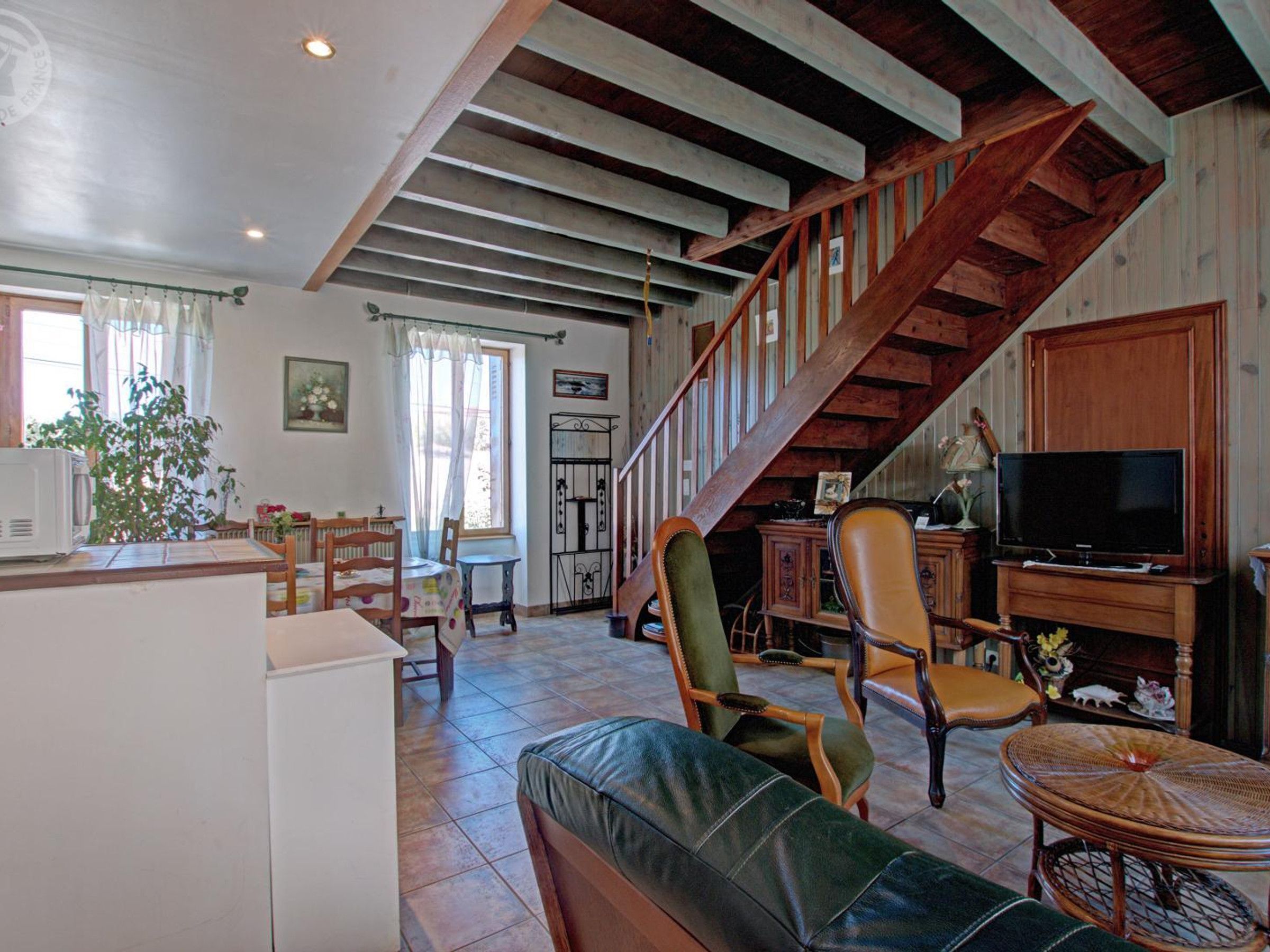 A spacious living area with a wooden staircase, a television, and a dining table.