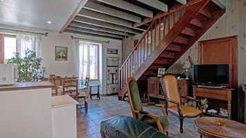 A spacious living area with a wooden staircase, a television, and a dining table.