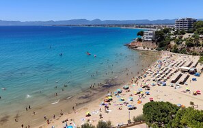 Una spiaggia con acque cristalline, una riva sabbiosa e una fila di ombrelloni.
