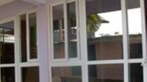 A building with large windows and a covered porch area with potted plants. - Shiloh Accommodation (Mombasa)