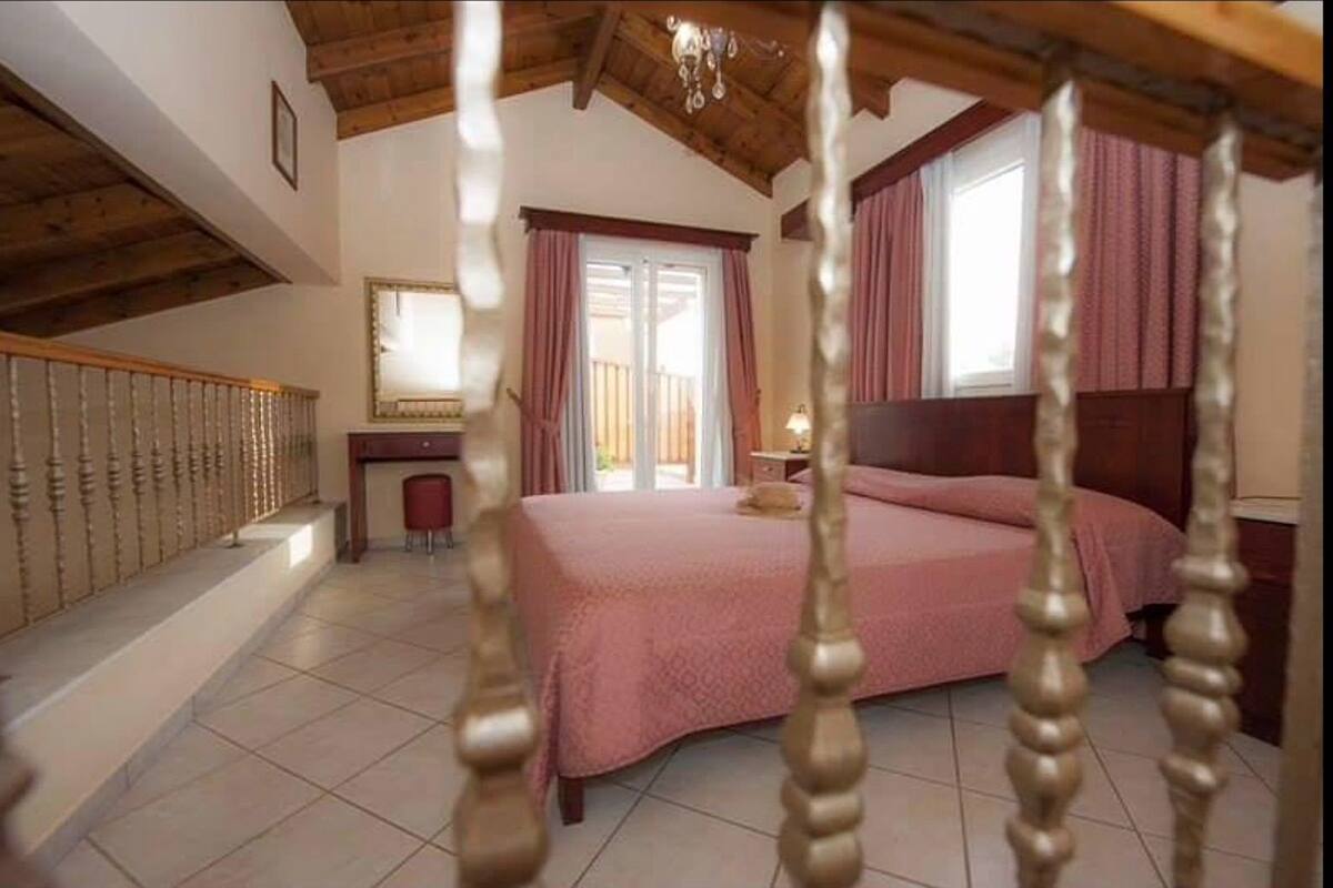 A bedroom with a large bed, a desk, and a window with curtains.