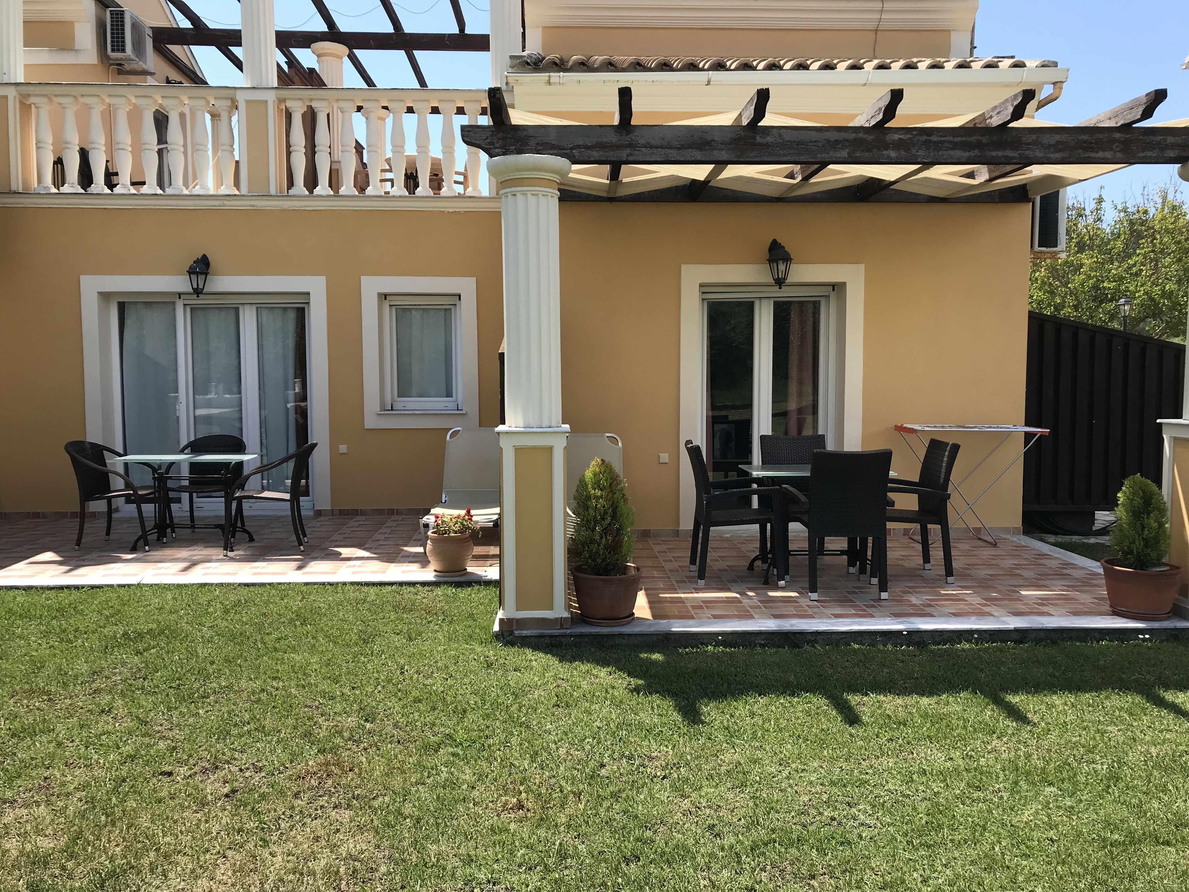 A patio area with outdoor furniture, a pergola, and potted plants.