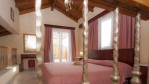 A bedroom with a large bed, wooden headboard, and a view of the outside through a sliding door. - L'Eremo Luxury Apartments (Corfu)