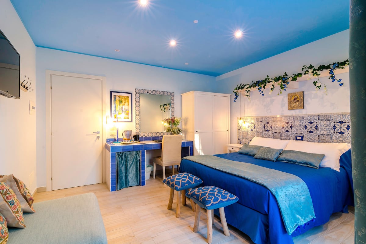 Une chambre à coucher avec un lit, un bureau et une chaise. Il y a une porte et un mur orné d’un motif décoratif.