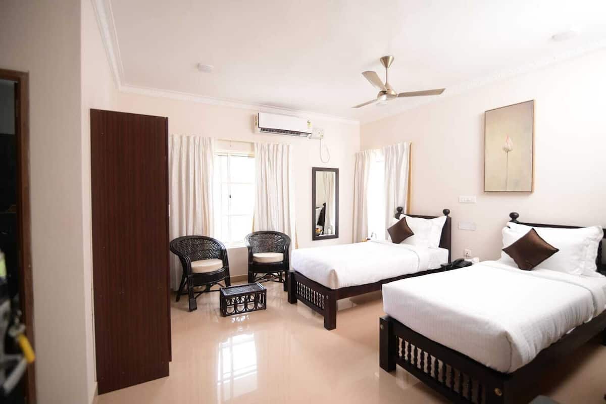 A hotel room with two beds, a ceiling fan, an air conditioning unit, and a large mirror.