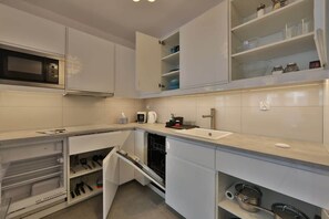A modern kitchen with white cabinets, a microwave, a dishwasher, and a sink.