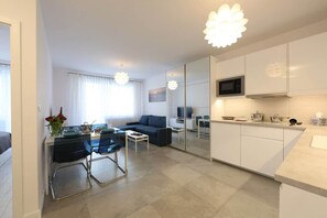 A modern kitchen with white cabinets, a microwave, and a dining area with a table and chairs.