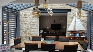 A dining area with a stone wall, wooden furniture, and hanging light fixtures.