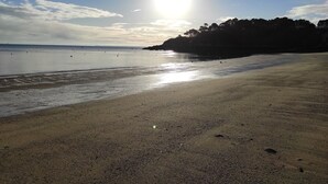 A beach with a clear sky and the sun shining.