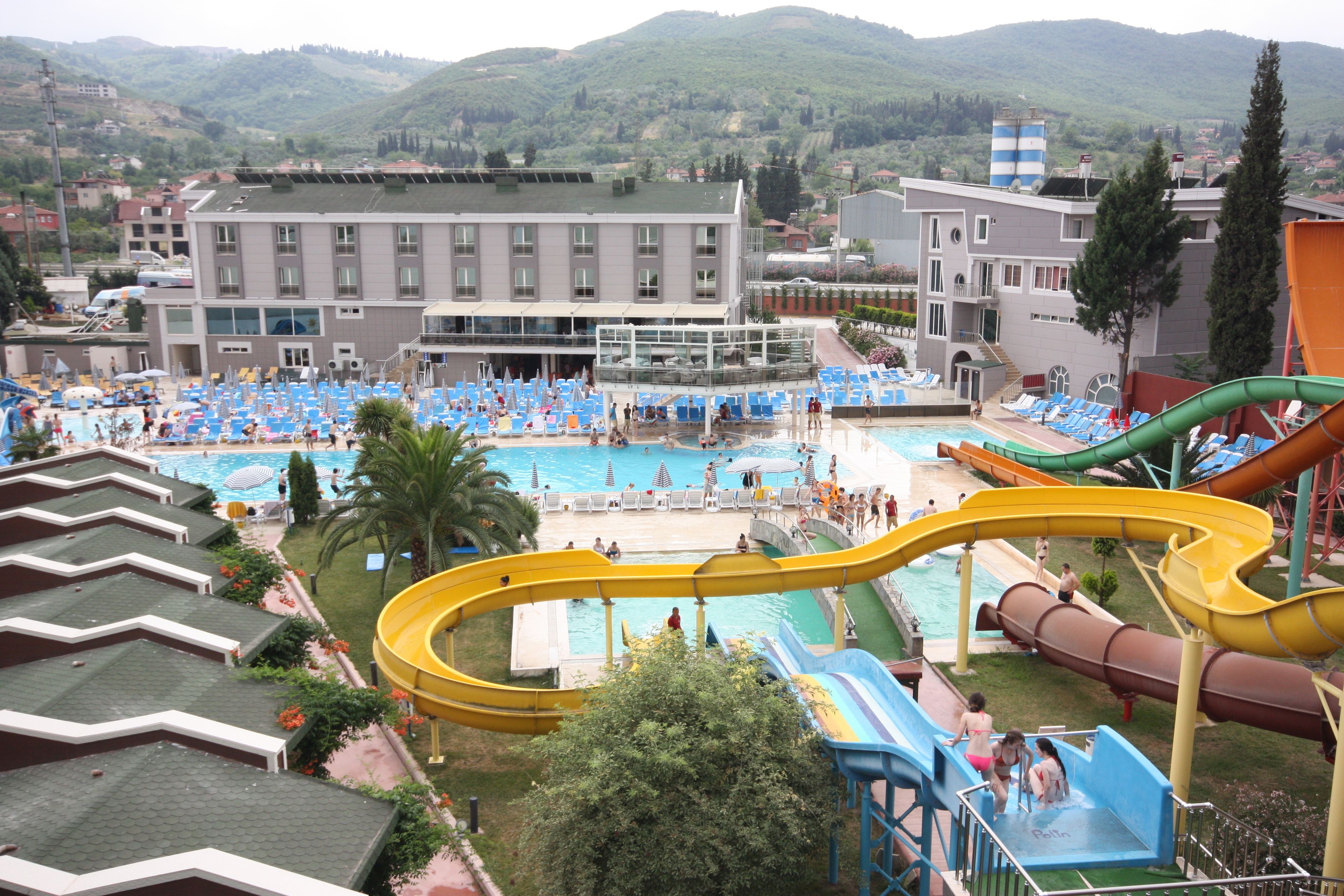 A resort with a large pool area, multiple water slides, and a view of surrounding hills.